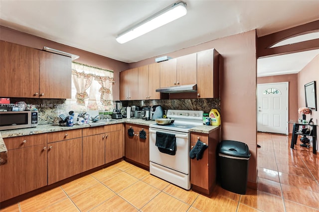 kitchen with white electric stove, light stone counters, backsplash, and light tile floors