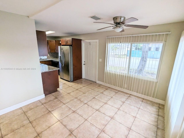 kitchen featuring light stone counters, backsplash, stainless steel refrigerator with ice dispenser, light tile flooring, and ceiling fan