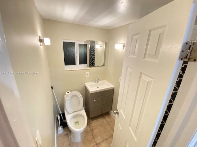 bathroom featuring tile flooring, vanity, and toilet