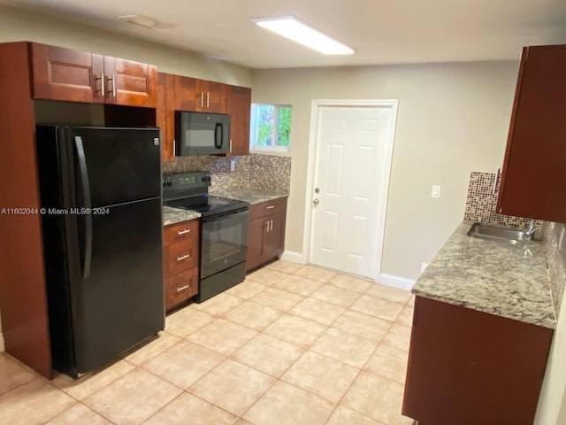 kitchen featuring light stone countertops, black appliances, backsplash, sink, and light tile floors