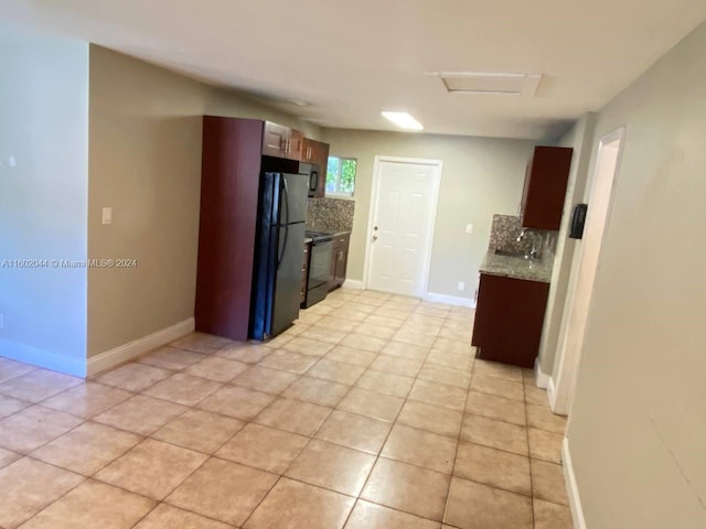 kitchen featuring light stone countertops, stainless steel fridge, electric range, backsplash, and light tile flooring