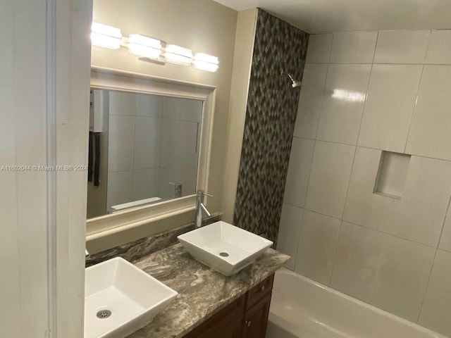 bathroom featuring vanity with extensive cabinet space and tiled shower / bath combo