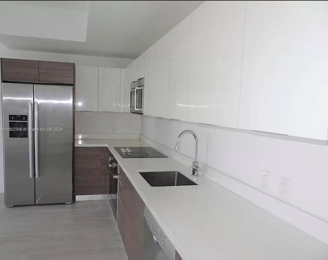 kitchen featuring appliances with stainless steel finishes, dark brown cabinetry, white cabinetry, and sink