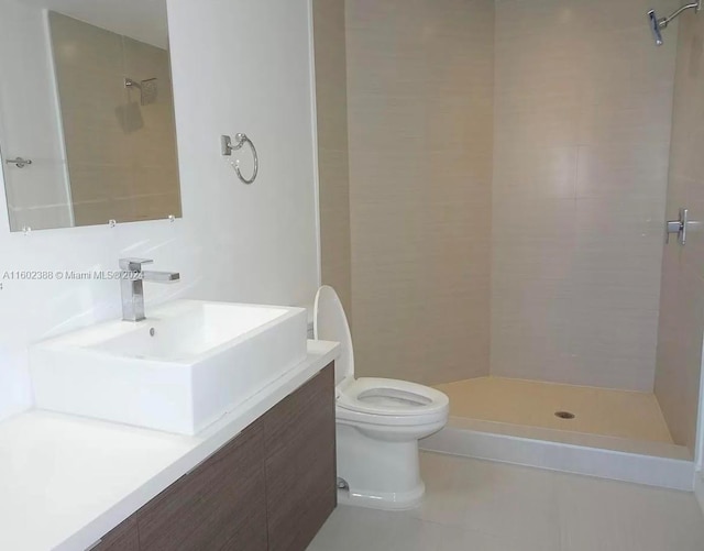 bathroom featuring tile patterned floors, vanity, toilet, and tiled shower