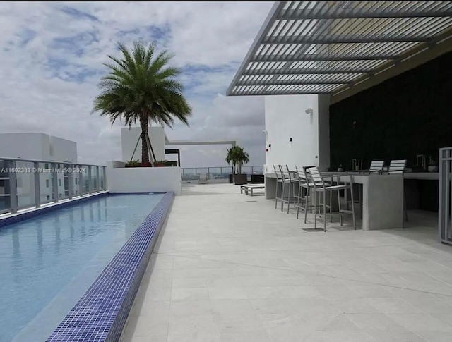 view of pool with a pergola, exterior bar, and a patio