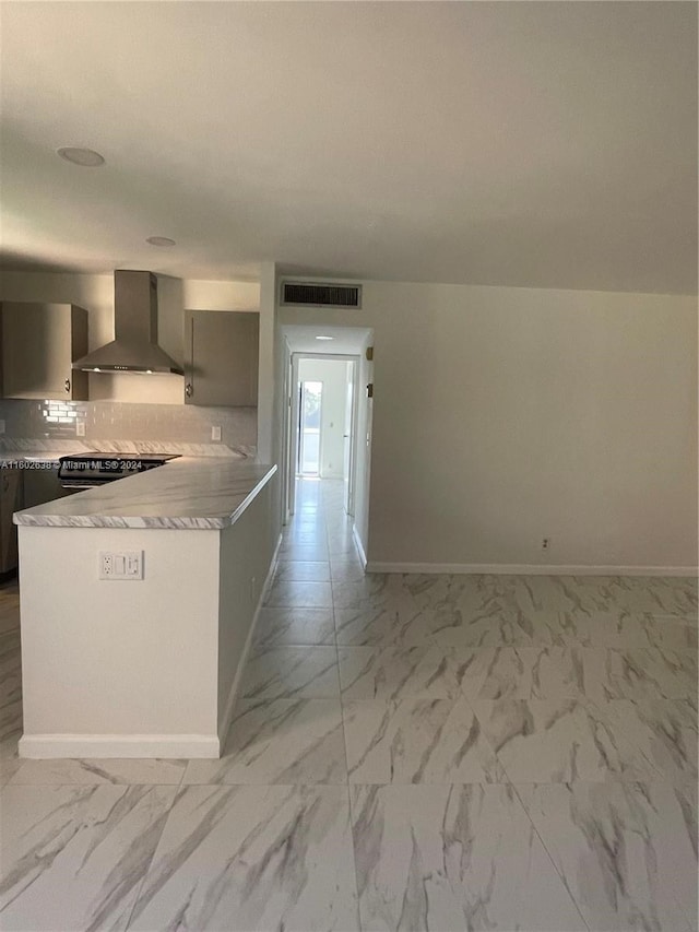 kitchen with decorative backsplash, kitchen peninsula, wall chimney exhaust hood, gray cabinets, and range with electric stovetop