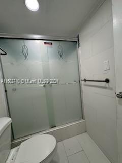 bathroom featuring tile patterned floors, toilet, and a shower with shower door