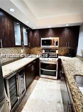 kitchen with dark brown cabinetry, light stone countertops, range, and tasteful backsplash