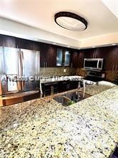 kitchen featuring appliances with stainless steel finishes, light stone countertops, and dark brown cabinetry