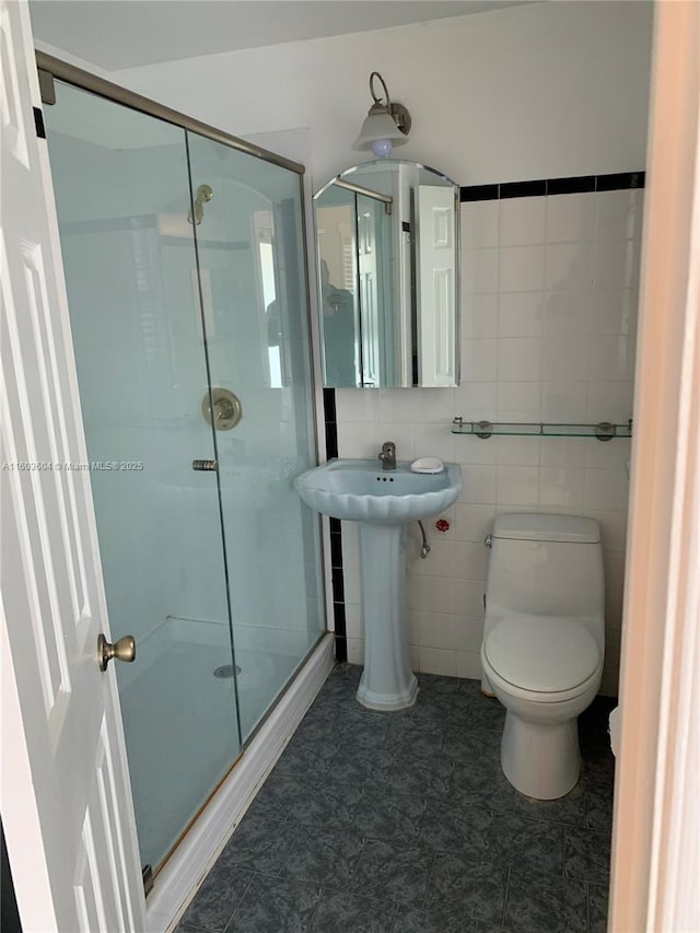 bathroom with an enclosed shower, tile walls, and toilet