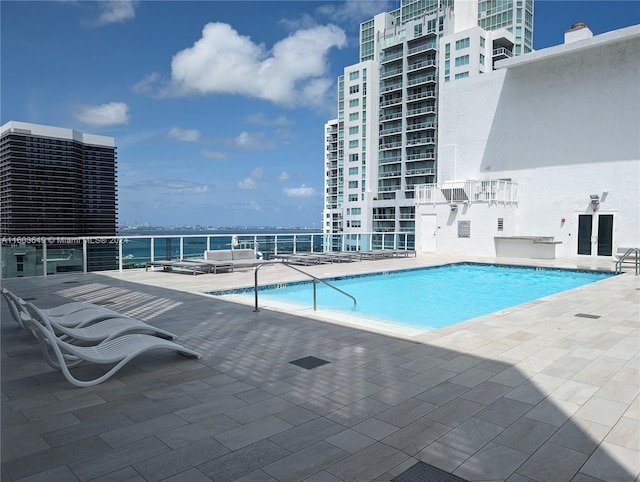 view of swimming pool with a water view and a patio area