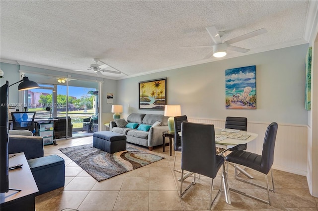 living room featuring a textured ceiling, ornamental molding, light tile flooring, and ceiling fan