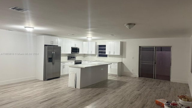 kitchen featuring white cabinets, appliances with stainless steel finishes, light wood-type flooring, and a kitchen island