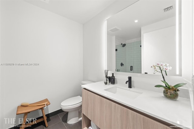 bathroom with tile floors, a tile shower, toilet, and vanity