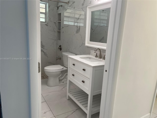 bathroom with vanity, toilet, and a tile shower