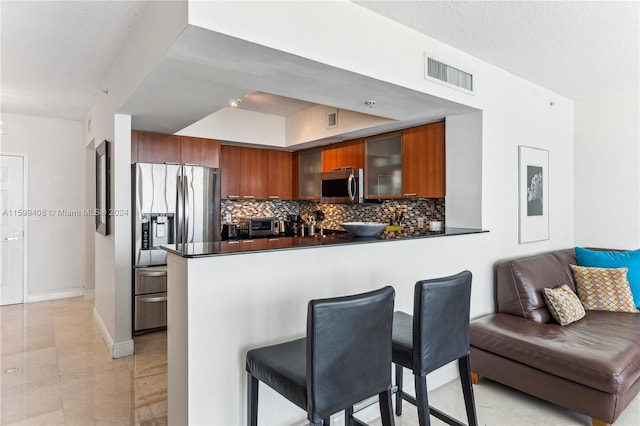 kitchen with backsplash, kitchen peninsula, stainless steel appliances, and a breakfast bar area