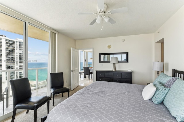 carpeted bedroom with a textured ceiling, a water view, ceiling fan, and access to outside