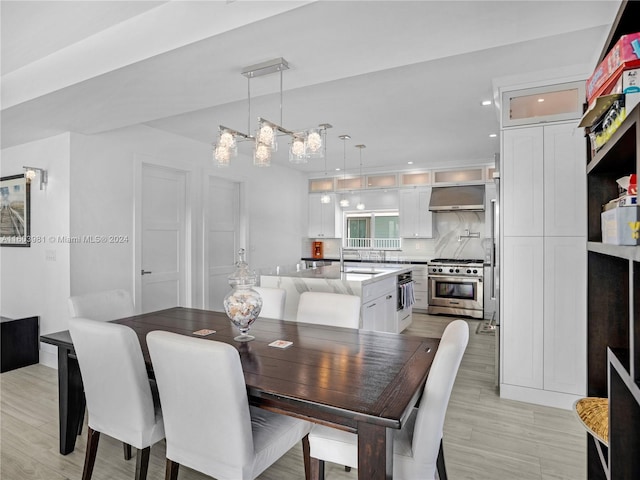 dining space with sink, light hardwood / wood-style flooring, and a notable chandelier