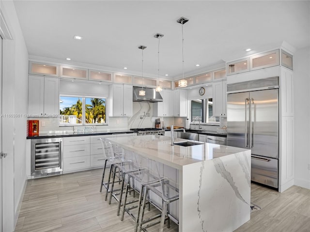 kitchen featuring wine cooler, white cabinets, pendant lighting, stainless steel appliances, and exhaust hood