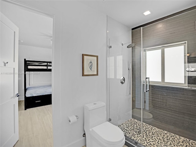 bathroom featuring wood-type flooring, toilet, and a shower with shower door