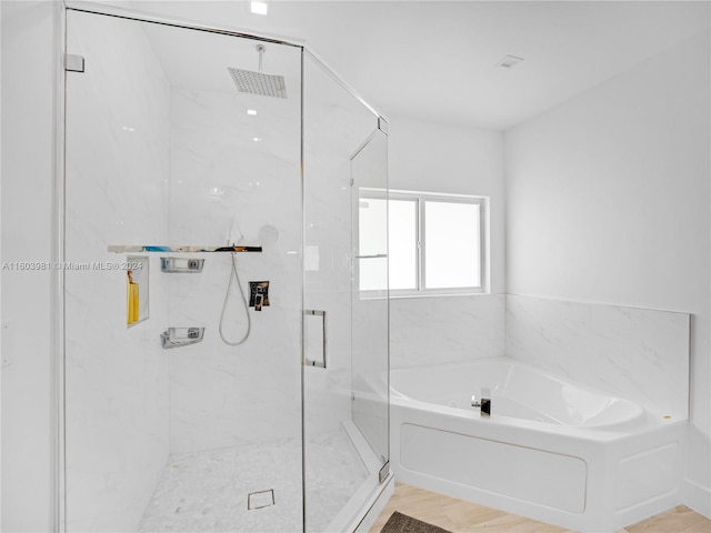 bathroom with wood-type flooring and shower with separate bathtub