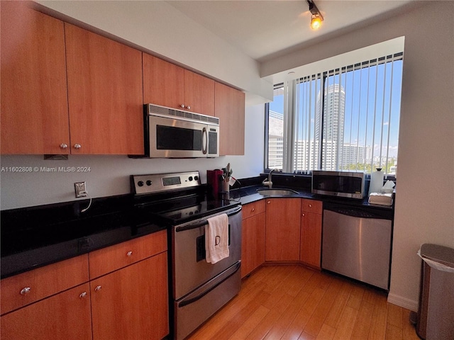 kitchen with appliances with stainless steel finishes, light wood-type flooring, and sink