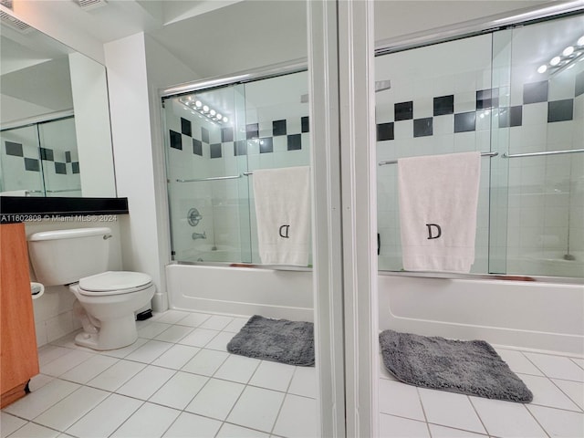 bathroom with toilet, tile patterned flooring, and combined bath / shower with glass door