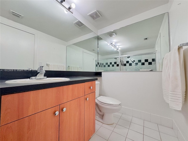 bathroom with toilet, a tile shower, vanity, and tile patterned floors