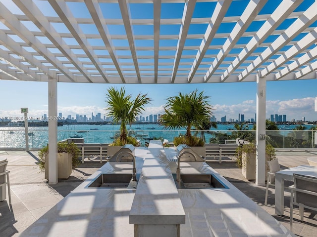 view of patio with sink, a pergola, and a water view