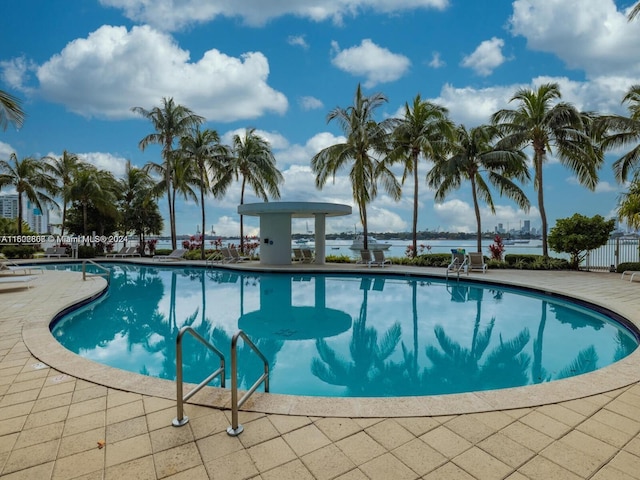 view of swimming pool featuring a water view and a patio area