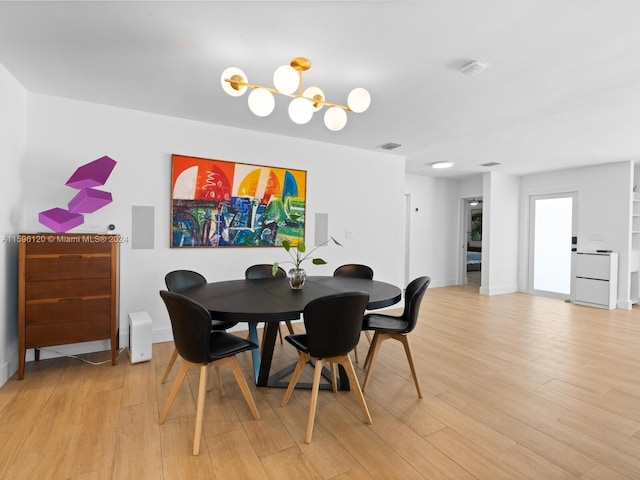 dining space featuring light wood-type flooring and a notable chandelier