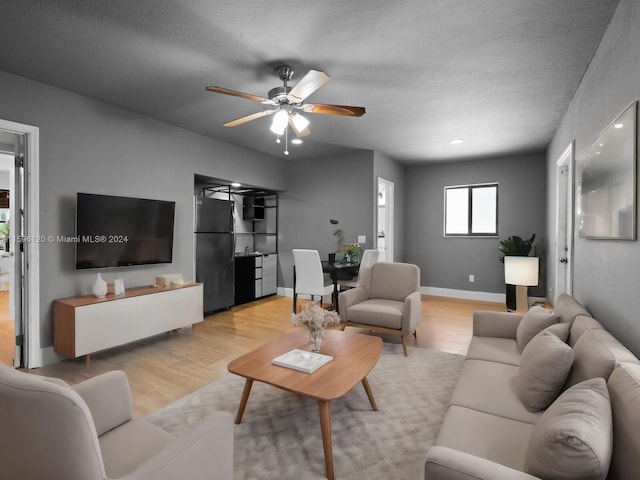 living room featuring a textured ceiling, ceiling fan, and light hardwood / wood-style flooring