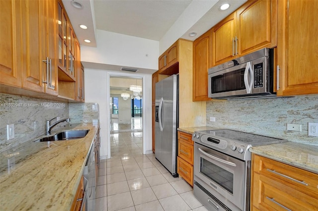 kitchen with sink, light stone counters, light tile patterned floors, appliances with stainless steel finishes, and backsplash