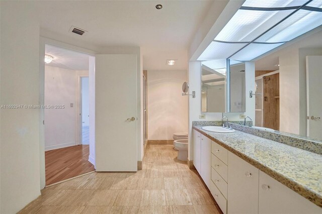 bathroom with a bidet, vanity, a shower with door, and toilet