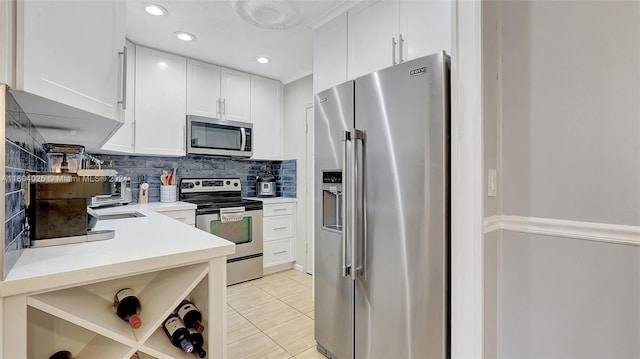 kitchen with stainless steel appliances, decorative backsplash, light tile patterned floors, and white cabinetry