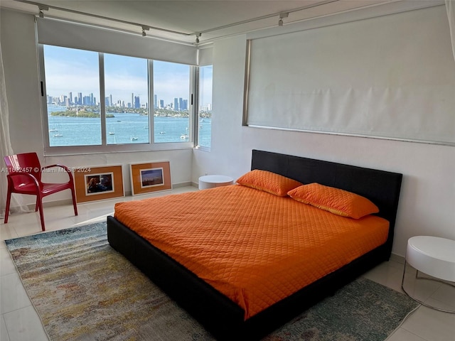 bedroom with a fireplace, a water view, and tile patterned flooring