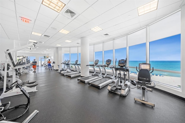 workout area featuring a paneled ceiling and a water view