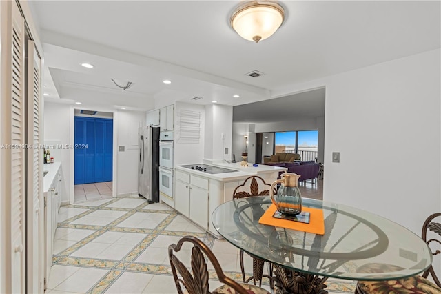 kitchen featuring double oven, white cabinets, black electric stovetop, and light tile floors