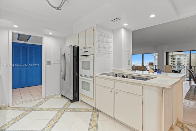 kitchen with double oven, black electric stovetop, stainless steel fridge, white cabinets, and light tile floors