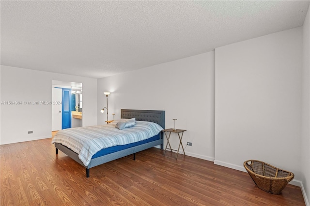 bedroom featuring a textured ceiling, ensuite bathroom, and hardwood / wood-style floors