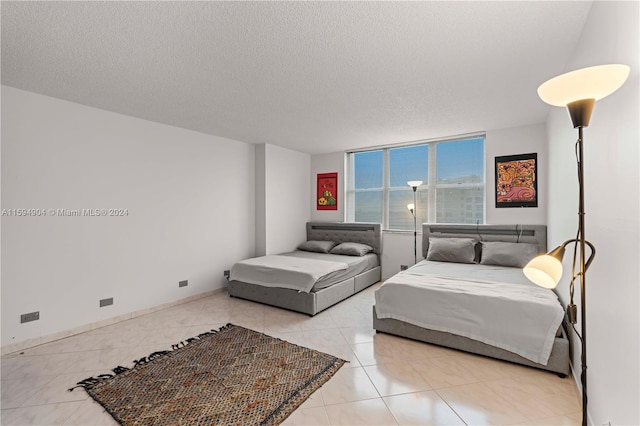 tiled bedroom featuring a textured ceiling and a wall of windows