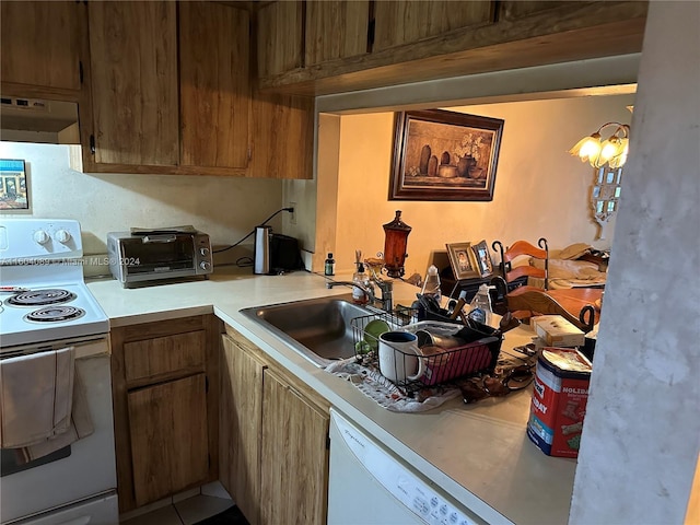 kitchen featuring white appliances, a toaster, brown cabinets, light countertops, and under cabinet range hood