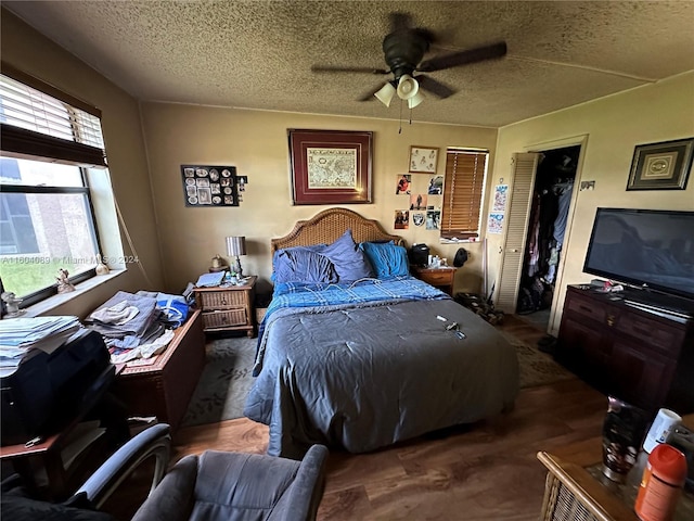 bedroom featuring a ceiling fan, dark wood finished floors, and a textured ceiling