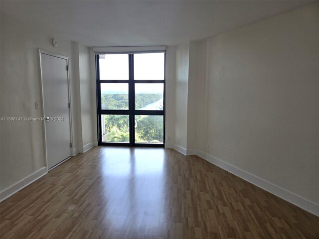 unfurnished room with floor to ceiling windows and dark wood-type flooring