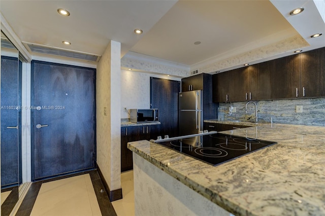 kitchen featuring appliances with stainless steel finishes, dark brown cabinets, backsplash, sink, and light tile floors