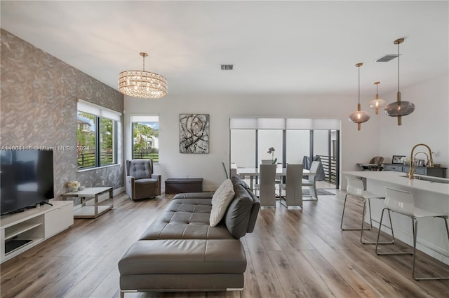 living room featuring sink, light hardwood / wood-style flooring, and a notable chandelier