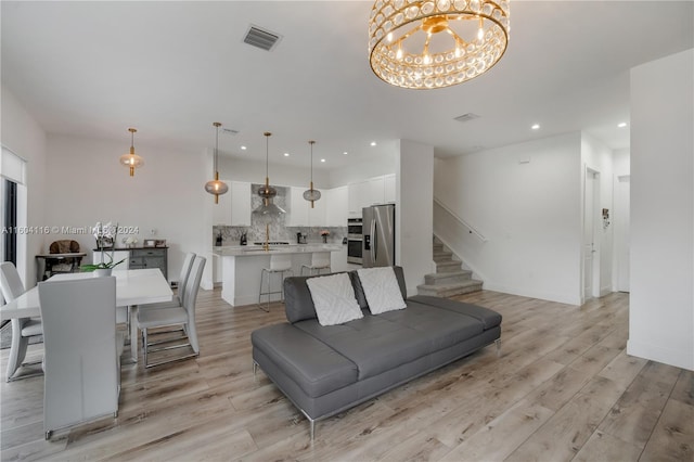 living room featuring a notable chandelier and light wood-type flooring