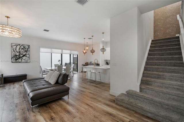 living room featuring an inviting chandelier, hardwood / wood-style flooring, and sink