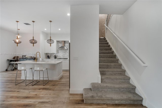 staircase featuring sink and hardwood / wood-style floors