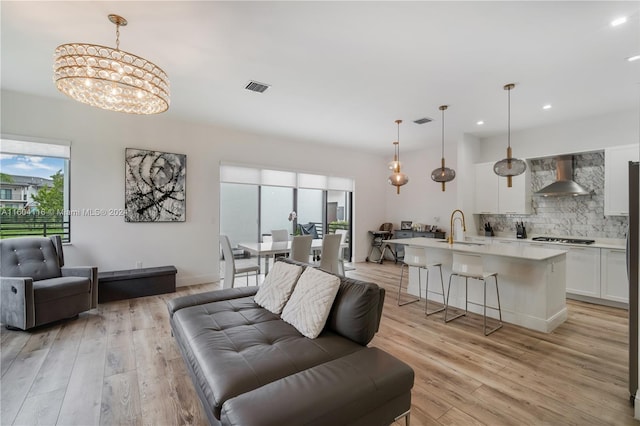 living room with light hardwood / wood-style flooring, a chandelier, and sink